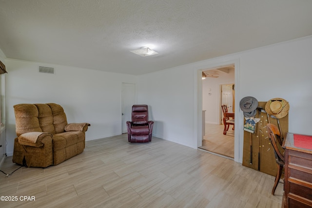 living area featuring light wood-style flooring, visible vents, and a textured ceiling