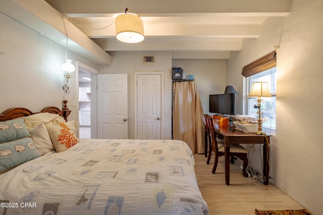 bedroom with beamed ceiling, light wood-style flooring, multiple windows, and visible vents