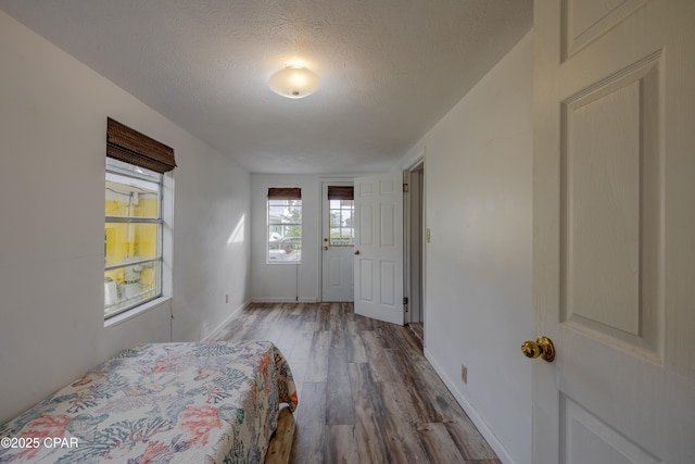 bedroom with a textured ceiling, baseboards, and wood finished floors