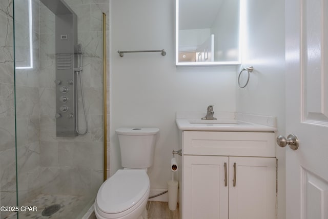 full bath with tiled shower, vanity, and toilet