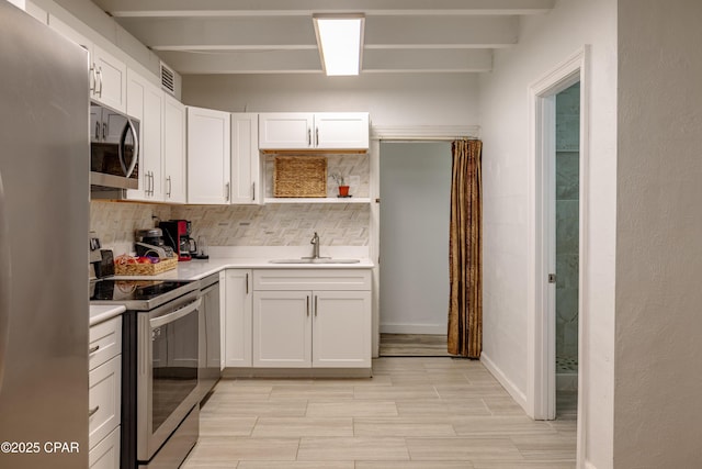 kitchen featuring appliances with stainless steel finishes, a sink, light countertops, white cabinetry, and backsplash