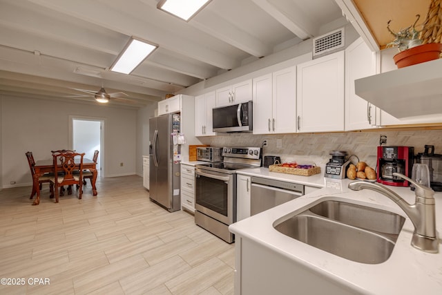 kitchen featuring visible vents, stainless steel appliances, light countertops, white cabinetry, and a sink