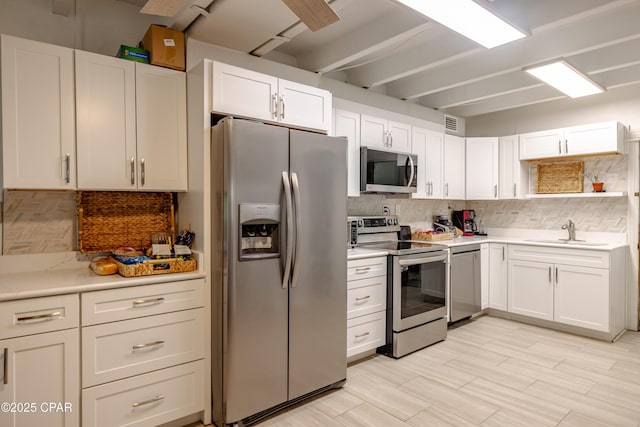 kitchen with stainless steel appliances, light countertops, a sink, and decorative backsplash