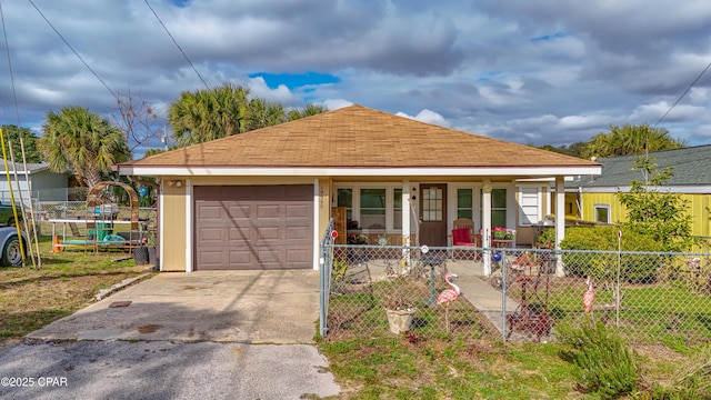 single story home featuring driveway, a fenced front yard, a porch, and an attached garage