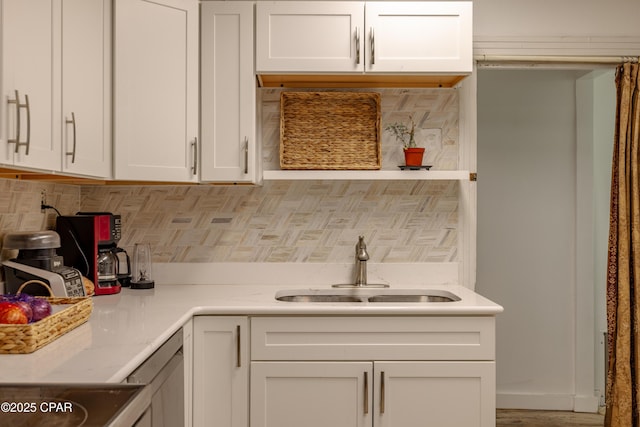 kitchen with tasteful backsplash, a sink, range, and white cabinets