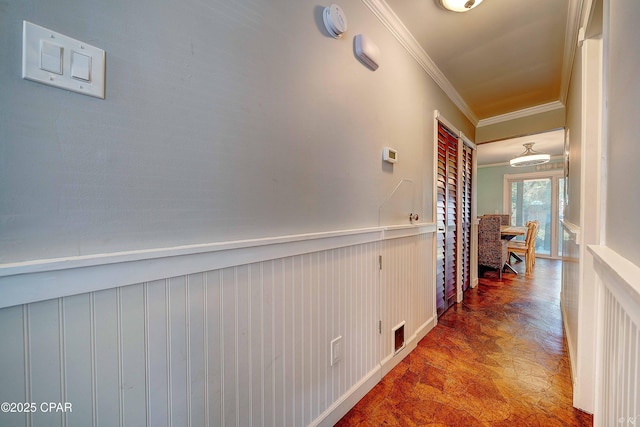 hallway featuring a wainscoted wall and crown molding