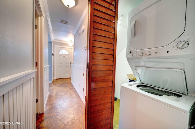 clothes washing area featuring laundry area, baseboards, visible vents, stacked washer and clothes dryer, and crown molding