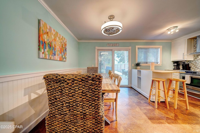 dining space featuring a wainscoted wall and ornamental molding