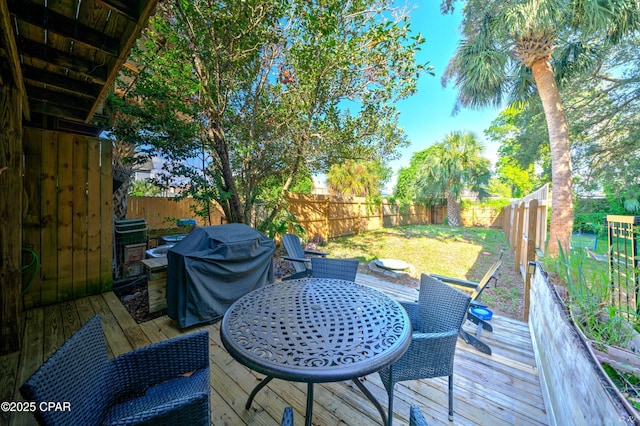 deck featuring outdoor dining space, area for grilling, and a fenced backyard