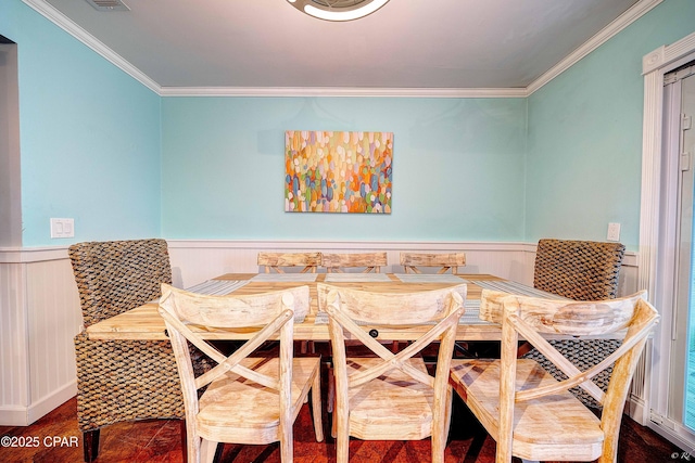 dining room featuring a wainscoted wall, ornamental molding, wood finished floors, and visible vents