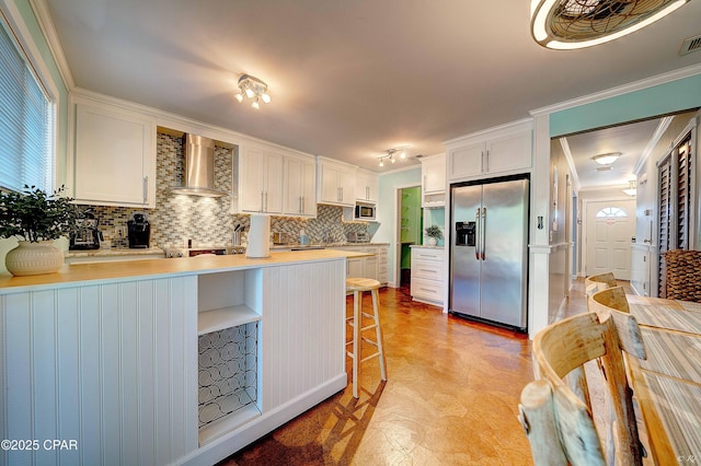 kitchen featuring stainless steel appliances, visible vents, ornamental molding, a peninsula, and wall chimney exhaust hood