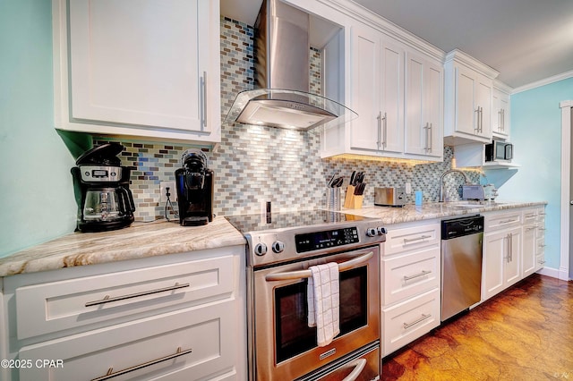 kitchen with tasteful backsplash, wall chimney exhaust hood, stainless steel appliances, white cabinetry, and a sink