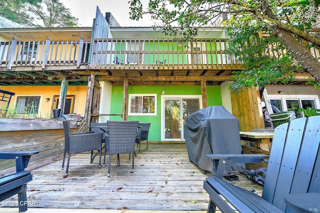 wooden terrace featuring outdoor dining space and grilling area