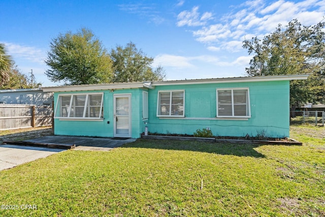 view of front facade with a front yard, concrete block siding, and fence