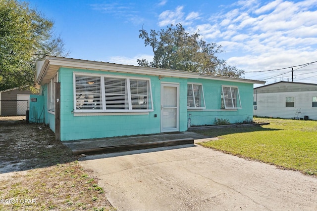 bungalow with a front lawn and concrete block siding