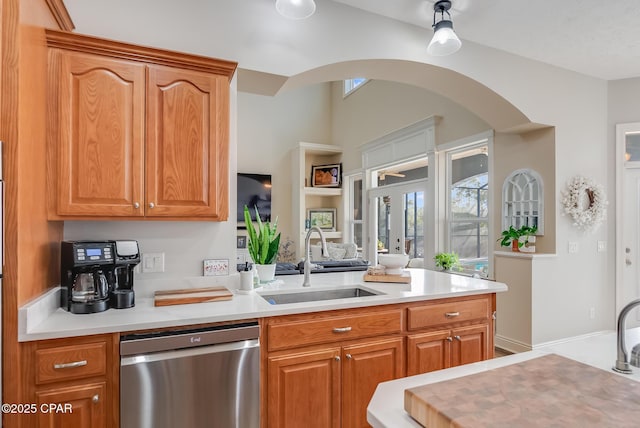 233 Moonlight Bay Dr, Panama City Beach, FL 32407 - kitchen featuring light countertops, brown cabinetry, stainless steel dishwasher, arched walkways, and a sink