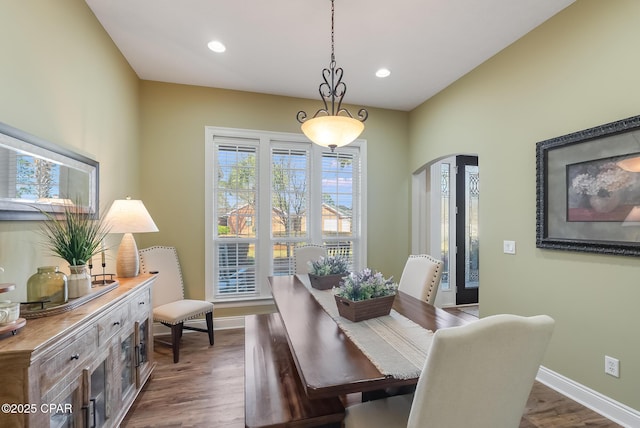 dining space featuring dark wood-style floors, baseboards, arched walkways, and recessed lighting