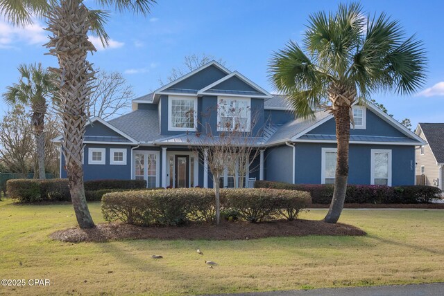 view of front of house featuring metal roof, a standing seam roof, a front yard, and stucco siding