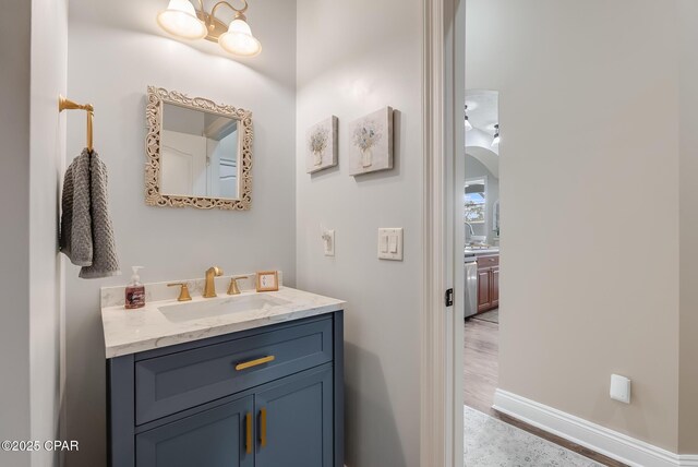 bathroom with an inviting chandelier, baseboards, wood finished floors, and vanity