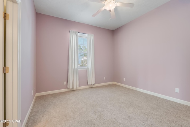 carpeted empty room featuring ceiling fan and baseboards