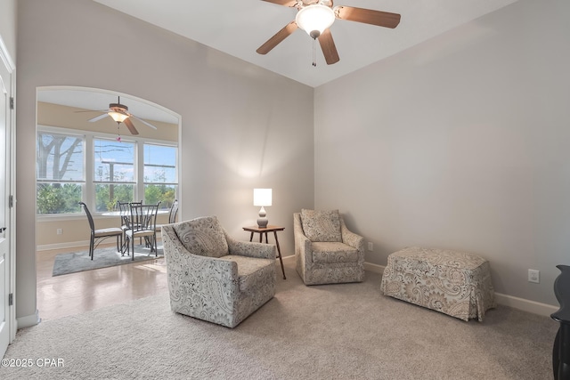 sitting room with ceiling fan, carpet, arched walkways, and baseboards