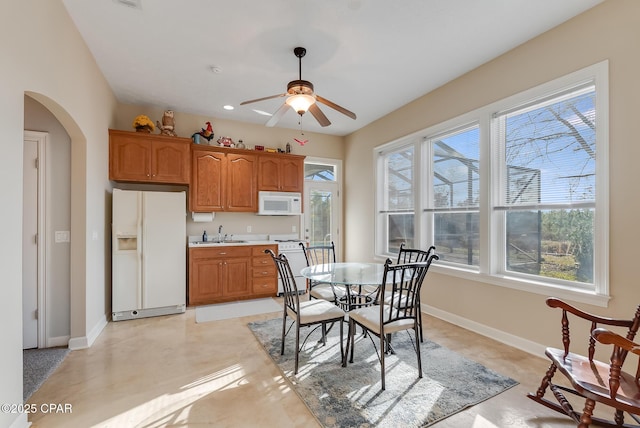 dining space featuring arched walkways, ceiling fan, baseboards, and recessed lighting