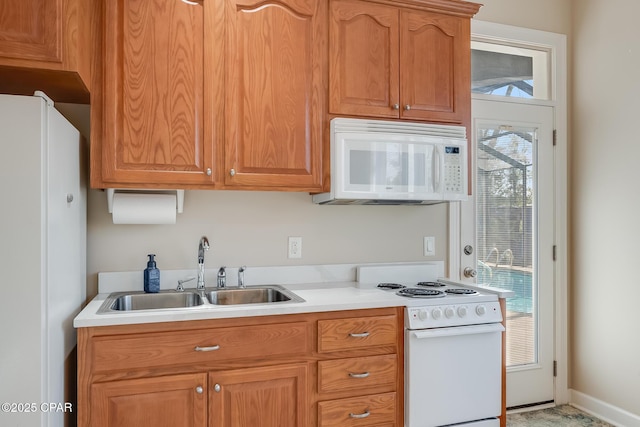 kitchen with white appliances, baseboards, light countertops, and a sink