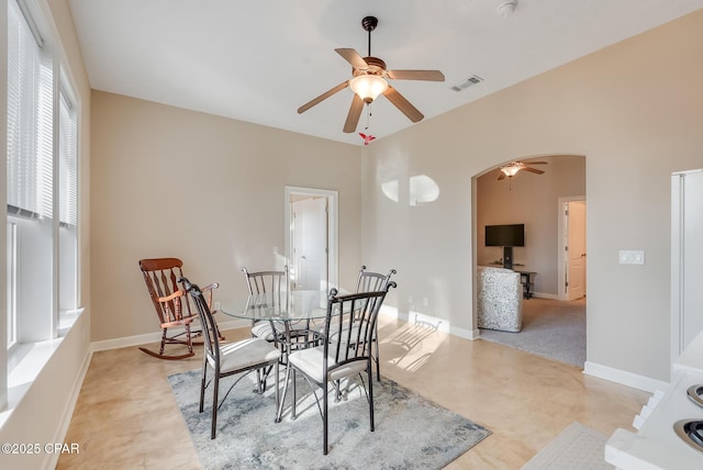 dining space with arched walkways, a ceiling fan, visible vents, and baseboards