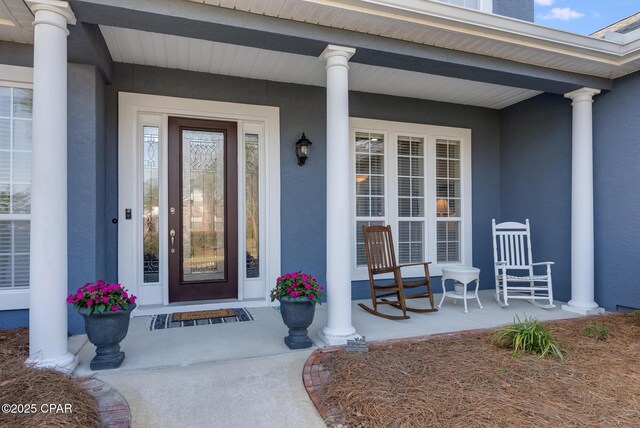 view of exterior entry with a porch and stucco siding