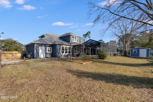 rear view of property with an outbuilding, a lawn, a storage shed, fence, and a lanai