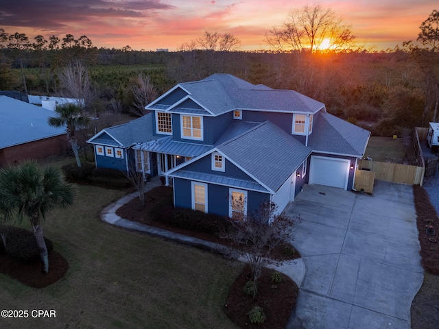 traditional-style home with metal roof, a garage, fence, driveway, and a standing seam roof