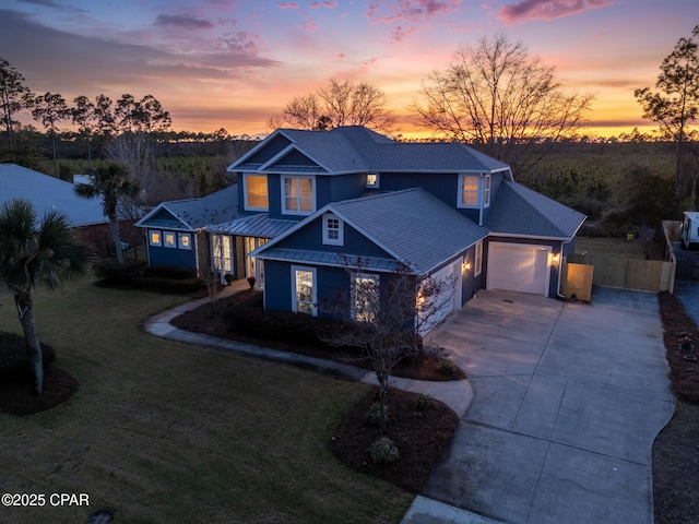 traditional home featuring a standing seam roof, metal roof, fence, a garage, and driveway