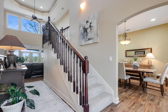 stairs featuring arched walkways, a healthy amount of sunlight, and wood finished floors