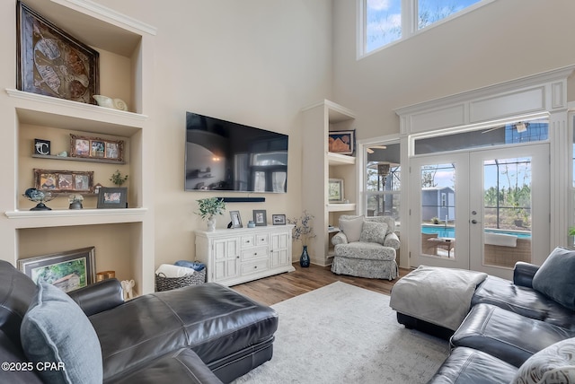 living area with a high ceiling, wood finished floors, and french doors