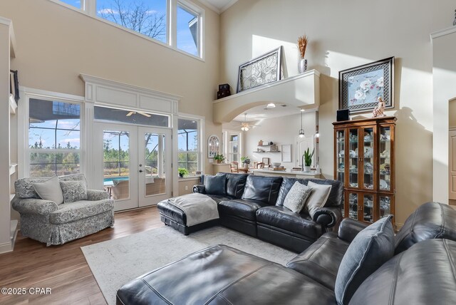 living room with french doors, a towering ceiling, and wood finished floors