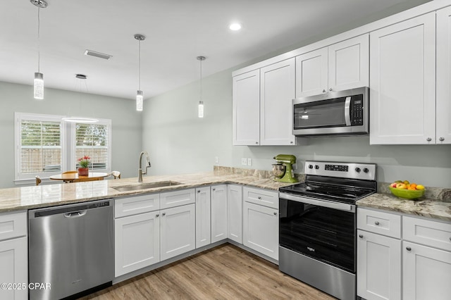 kitchen featuring light wood finished floors, visible vents, appliances with stainless steel finishes, white cabinetry, and a sink