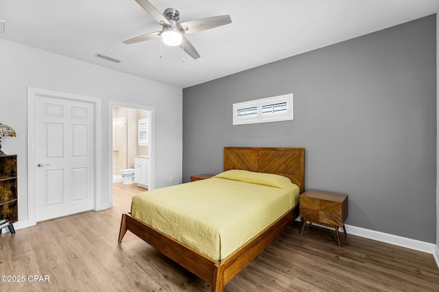 bedroom featuring light wood finished floors, baseboards, visible vents, a ceiling fan, and ensuite bathroom