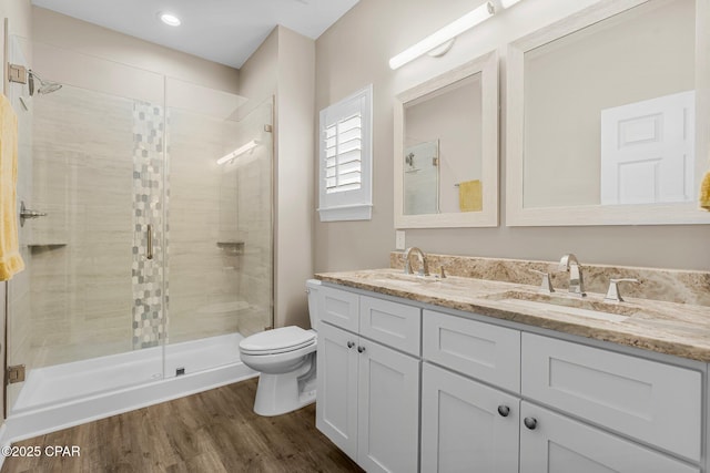 full bath with a stall shower, a sink, toilet, and wood finished floors