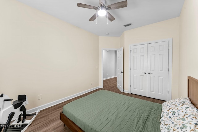 bedroom with baseboards, visible vents, dark wood finished floors, ceiling fan, and a closet