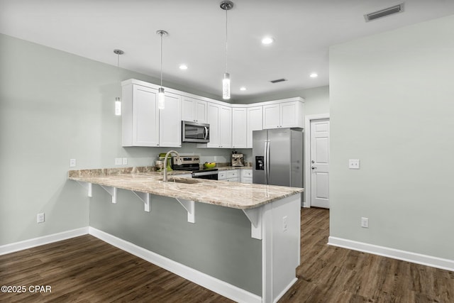 kitchen with stainless steel appliances, visible vents, a sink, a peninsula, and a kitchen breakfast bar