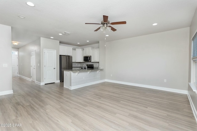 unfurnished living room featuring light wood-style floors, visible vents, baseboards, and recessed lighting