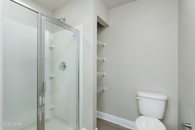 full bath featuring a stall shower, baseboards, toilet, and wood finished floors