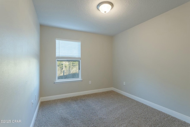 empty room featuring carpet floors, a textured ceiling, and baseboards