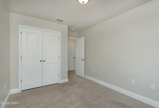 unfurnished bedroom featuring baseboards, visible vents, carpet, a textured ceiling, and a closet