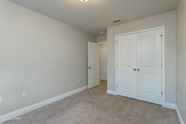 unfurnished bedroom with a closet, carpet, visible vents, and baseboards