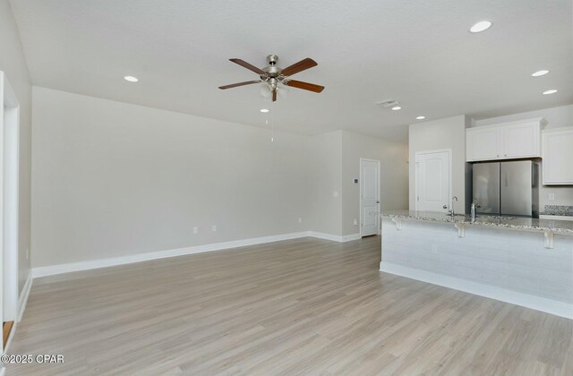 unfurnished living room with ceiling fan, recessed lighting, visible vents, baseboards, and light wood-style floors