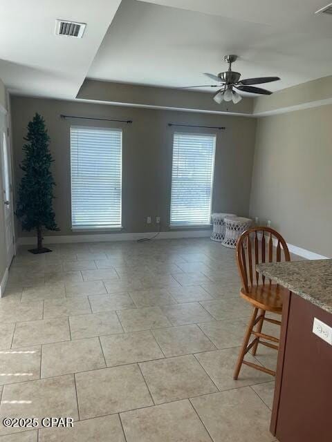 interior space with ceiling fan, visible vents, and baseboards