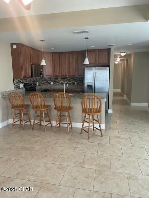 kitchen with a breakfast bar, black range with electric stovetop, a peninsula, and decorative backsplash