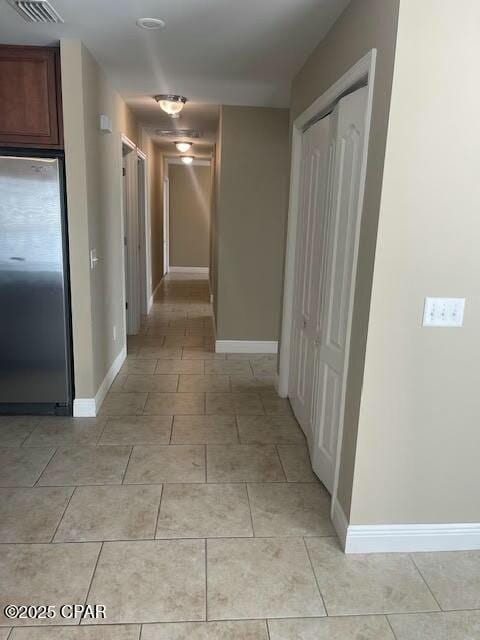 corridor with light tile patterned flooring, visible vents, and baseboards