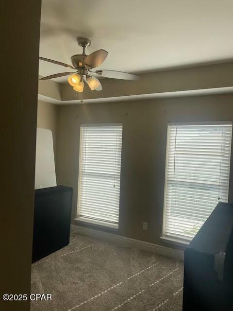 carpeted spare room with ceiling fan, baseboards, and a tray ceiling